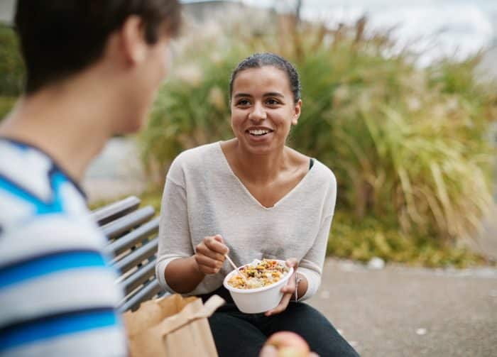 Vacances d'été - Quelles sont les dates de fermeture des lieux de restauration ? 1 Deux étudiants qui mangent sur un banc.